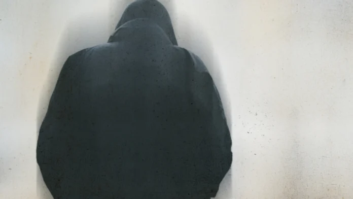 a depressed man in a hoodie with his back turned to the camera