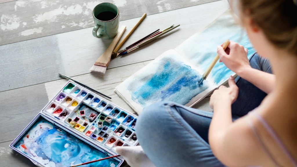 a woman paints using watercolors