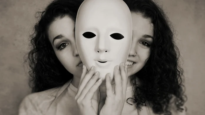 A woman poses behind a mask with 2 different expressions, signifying bipolar disorder