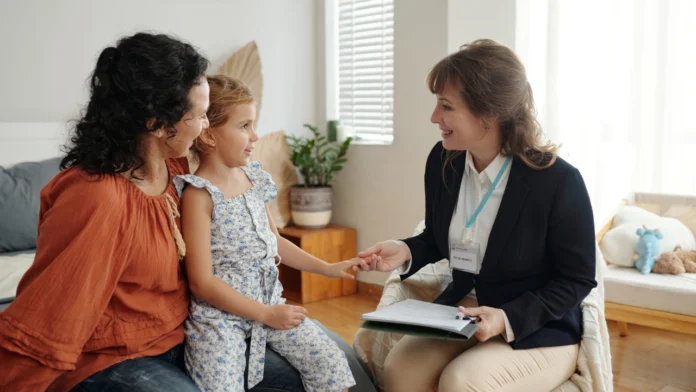 A social worker speaks with a parent and a child in her office