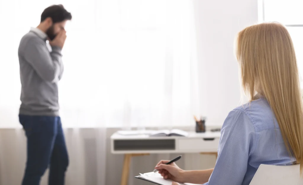 A man paces and covers his face as he speaks with a doctor