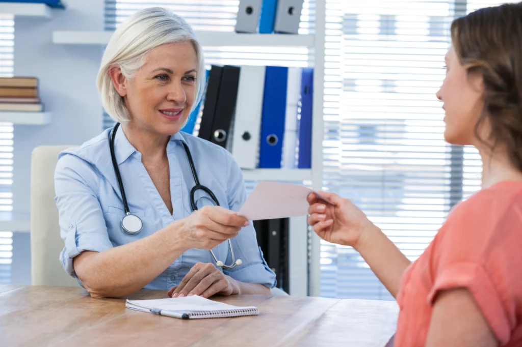 A doctor hands a prescription over to their patient