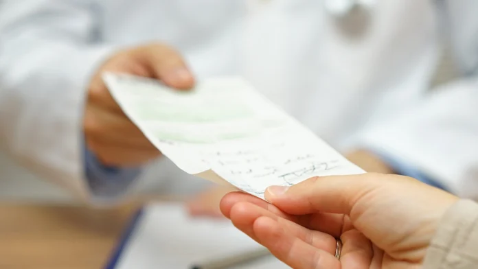 A doctor hands a prescription over to their patient