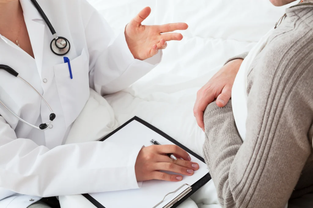 A doctor speaks with a patient while taking notes during an appointment