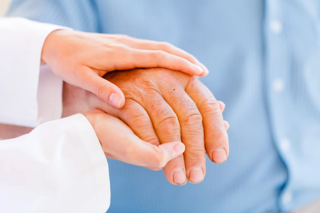A person comforts another by holding their hand