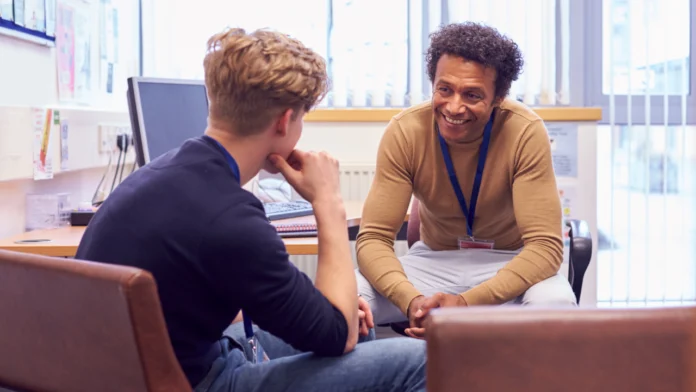 A mental health counselor smiles while speaking with a client