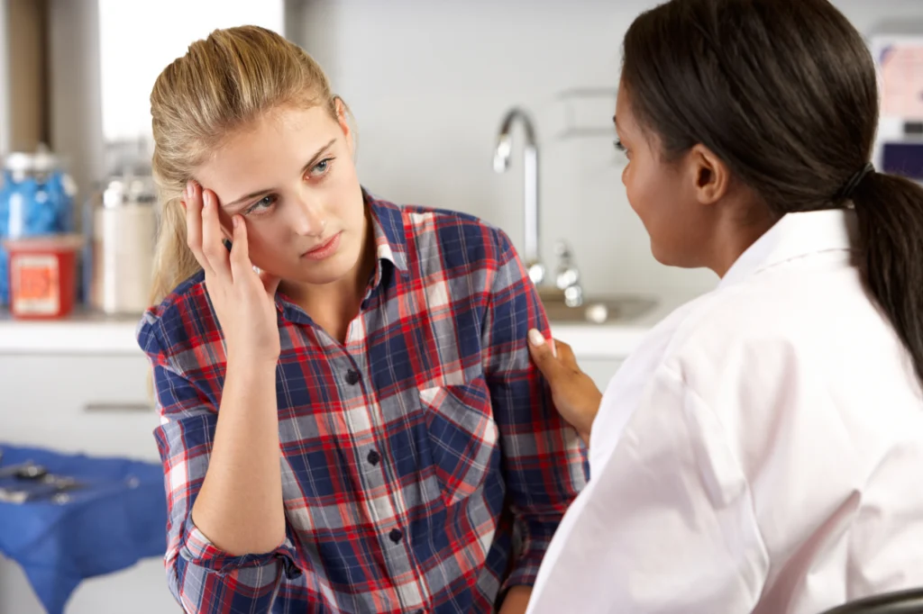 A stoic woman speaks with her doctor during a consultation