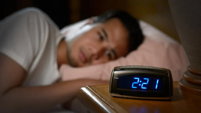 a man with insomnia sits awake in the early hours of the morning