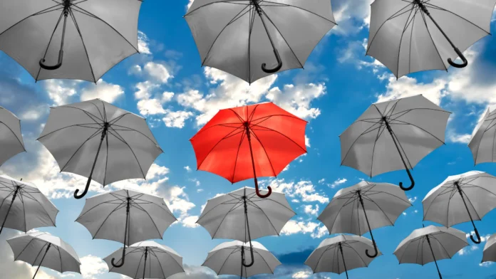 A unique red umbrella in a crowd of grey umbrellas