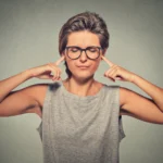 A person plugs their ears, refusing to hear critique. Learn more about passive aggression and related behaviors here.