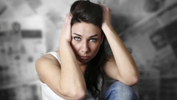 A stressed-out woman clutches her head. Knowing the difference of stress vs burnout can make a huge difference in your life