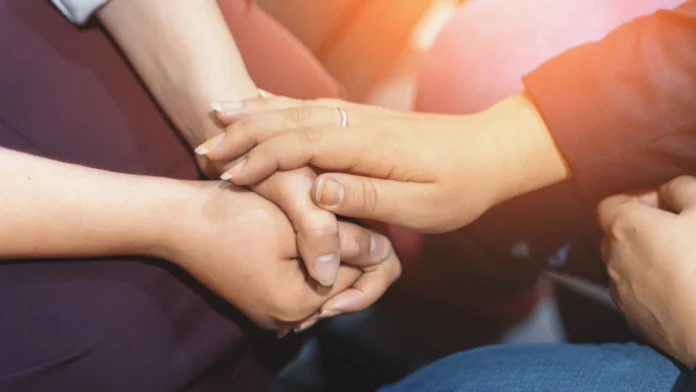 People holding hands at a counseling session. Learn more about cancer counseling and support here.