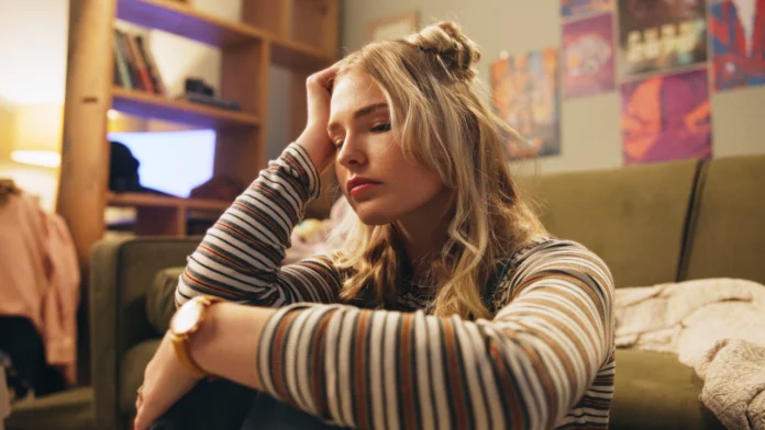 An anxious woman grips her head. Learn more about high functioning anxiety here.