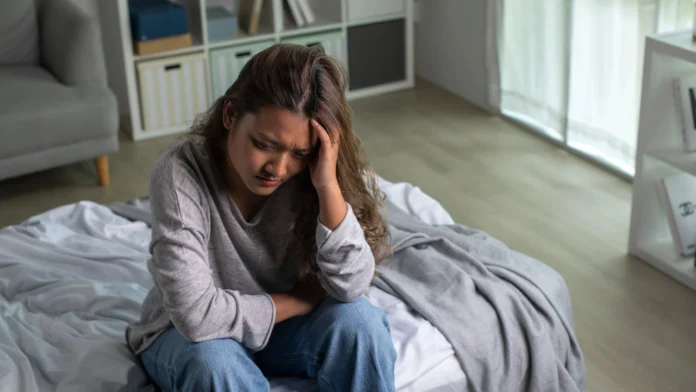 A depressed woman grips her head. Learn more about postpartum anxiety vs postpartum depression, here.